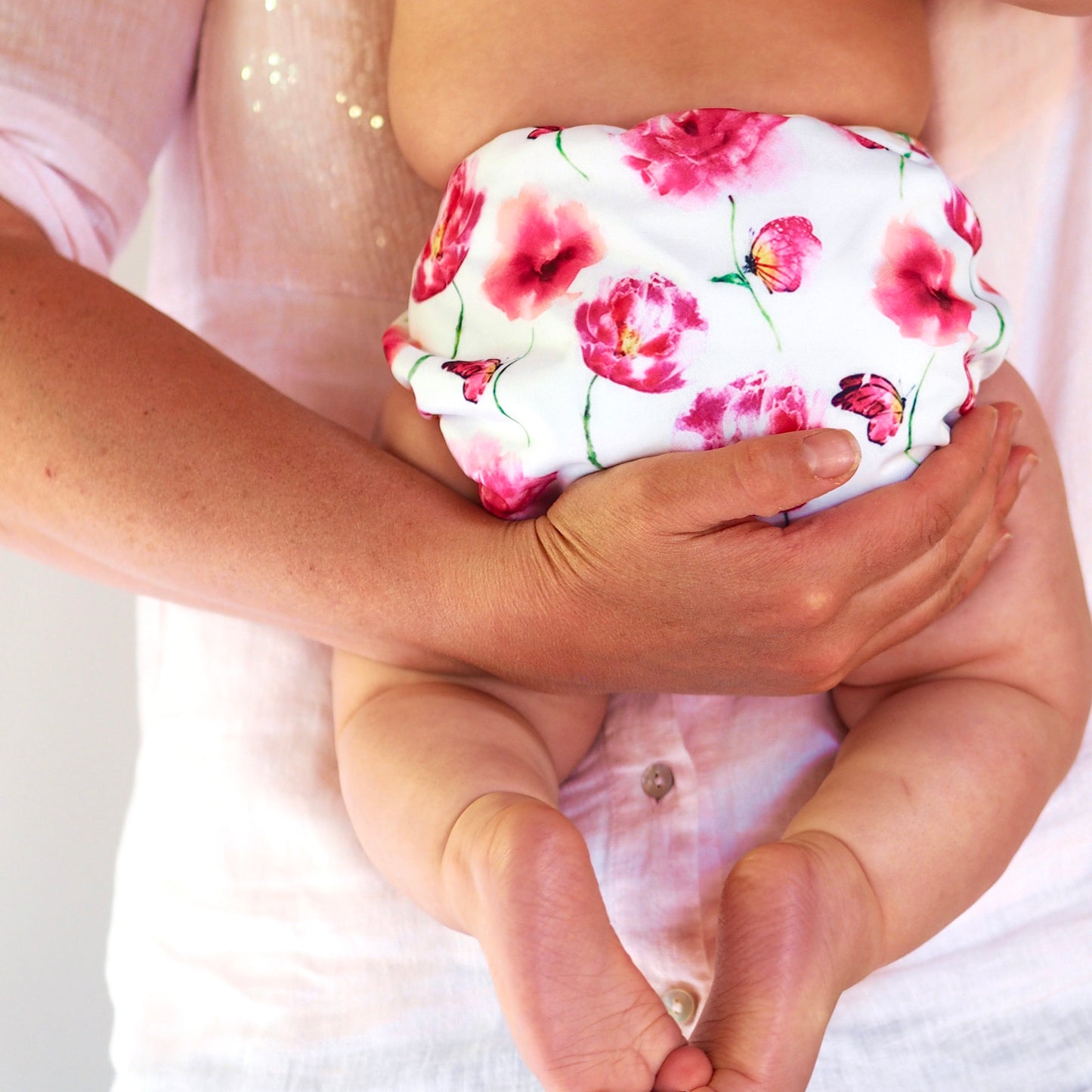Parent holding young baby wearing a cloth nappy.