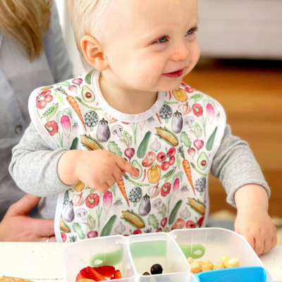 Baby wearing a bib eating vegetables