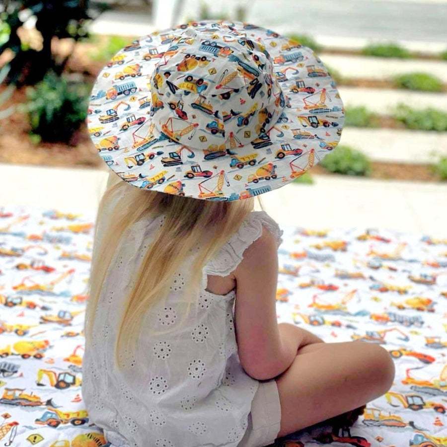 Little girl sitting on a play mat wearing a matching hat. 