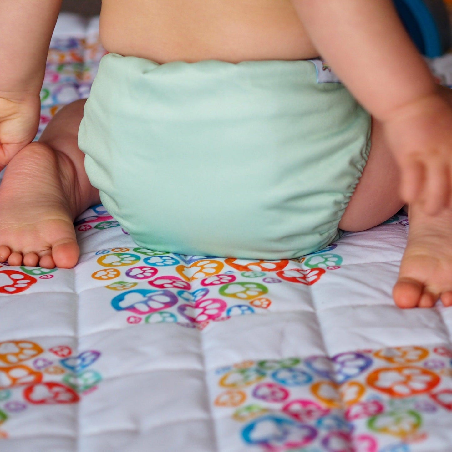 Picture of a baby from behind with their legs curling around their nappy. 