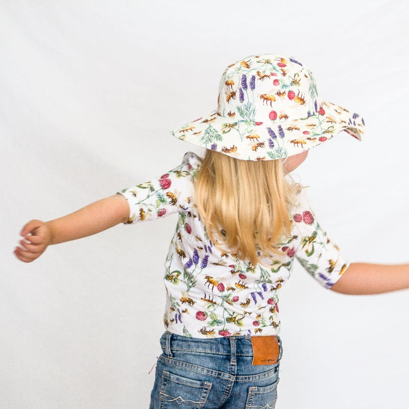 Little girl wearing shirt and wide brim hat.