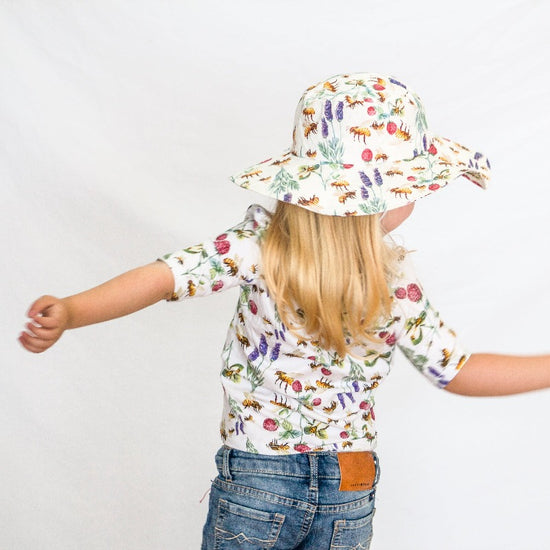 Little girl wearing shirt and wide brim hat.