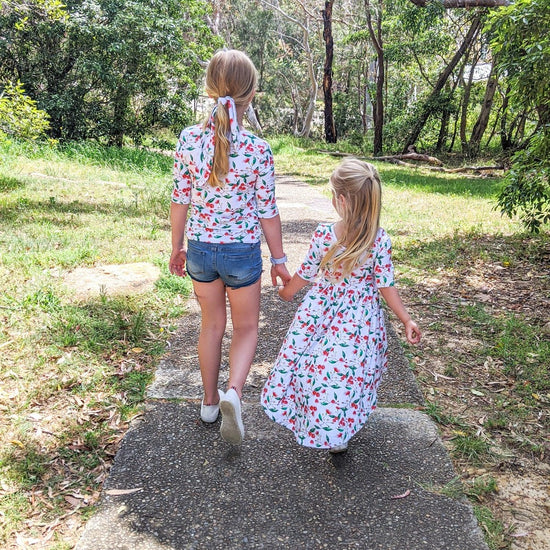 Two girls holding hands walking together wearing matching clothes