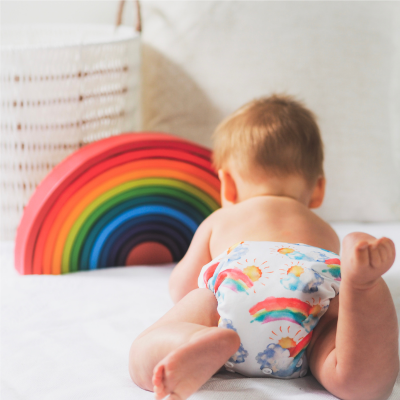 Baby with rainbow nappy playing with a rainbow. 