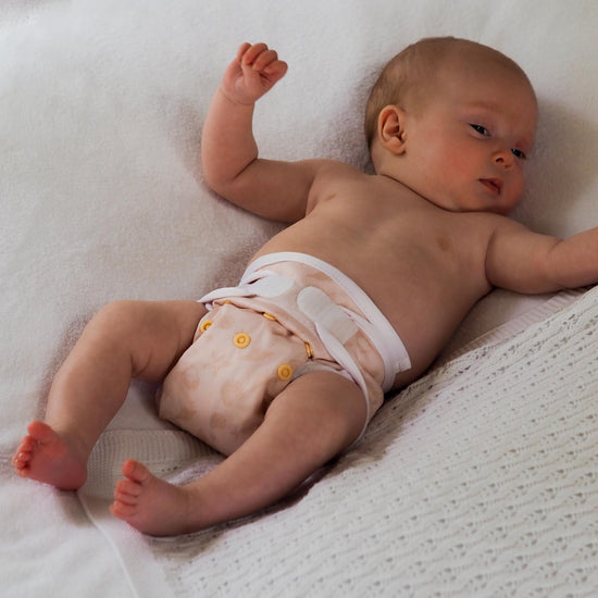 Newborn baby wearing cloth nappy on white blanket